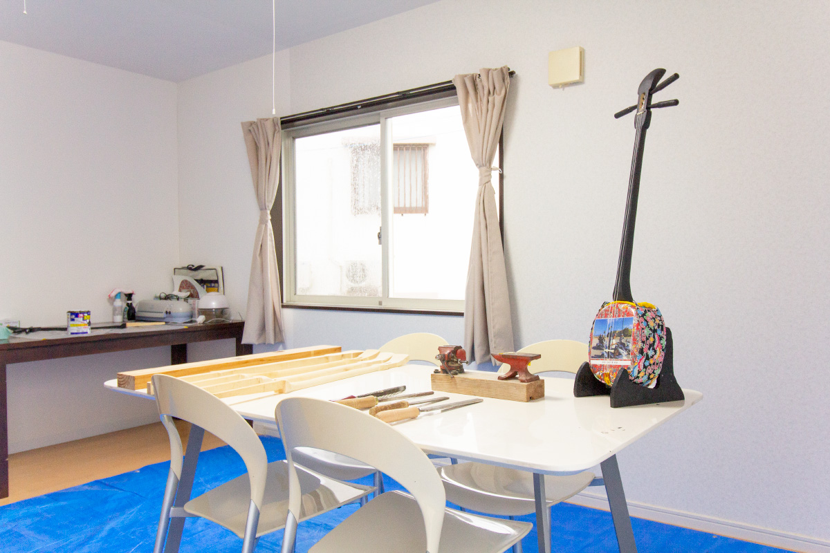 明るい日差しの入る白い壁の作業部屋。